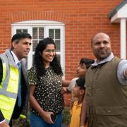 Rishi Sunak poses for a picture with Jai John Jose (right) and the Mathew family during a visit to the Taylor Wimpey Heather Gardens housing development in Hethersett