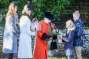 The Queen is given flowers by young well-wishers after the Christmas Day church service at Sandringham
