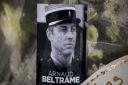 A photo of Lieutenant Colonel Arnaud Beltrame placed on a bunch of flowers at the main gate of the Police headquarters in Carcassonne. Lt Col Beltrame was hailed as as a national hero of 