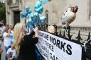 A Charlie Gard supporter ties blue balloons to the fencing outside the Royal Courts of Justice in London. Picture: Jonathan Brady/PA