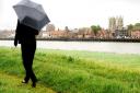 A walker sets off in the rain along the bank at West Lynn, with a backdrop of King's Lynn. Picture: Ian Burt