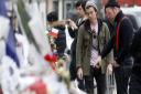 Members of the band Eagles of Death Metal, Jesse Hughes, right, and Julian Dorio pay their respects to 89 victims who died in a Nov. 13 attack at the Bataclan concert hall in Paris, France, Tuesday, Dec. 8, 2015. Members of the California rock band Eagles