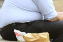 File photo dated 28/07/10 of an overweight man eating fast food, as councils have warned they cannot afford to tackle the growing obesity 