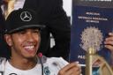 Mercedes driver Lewis Hamilton holds up an oversized, mock Brazilian passport given to him by TV comedians during a press conference in Sao Paulo - ahead of this weekend's Brazilian Grand Prix.