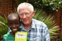 Miracle boy Musa displays his Thanks A Million card for EDP readers as he gets a hug from TVs Nick Hewer in Rwanda.Picture: James Ruddy