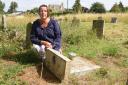 Louise Earl with her grandparents' headstones which has been deemed unsafe and pushed over, at Redenhall Church