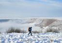 A person walks through snow above the Hole of Horcum at the North York Moors National Park (Danny Lawson/PA)