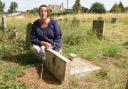 Louise Earl with her grandparents' headstones which has been deemed unsafe and pushed over, at Redenhall Church