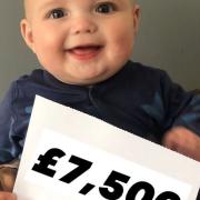 Baby Preston is all smiles as he proudly displays the total amount raised for Gorleston's JPUH neo natal unit at Spencer's Sports Bar in memory of his twin sister Ivy who was stillborn.