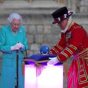 Queen Elizabeth II symbolically leads the lighting of the principal Jubilee beacon at Windsor Castle. The cushion on which the crown and globe rest was made in Felmingham, north Norfolk, by Jon Rhodes