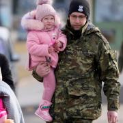 A Polish border guard carries a child as refugees from Ukraine cross into Poland at the Medyka crossing.