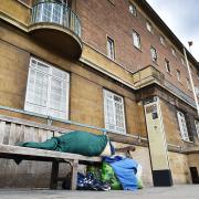 A homeless person sleeping rough on a bench outside Norwich City Hall.