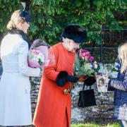The Queen is given flowers by young well-wishers after the Christmas Day church service at Sandringham