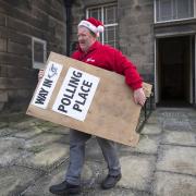 Brian Mansley carries a sign, one of hundreds that are being dispatched to polling stations around Scotland from the Old Royal High School in Edinburgh, ahead of the General Election. PA Photo. Picture date: Wednesday December 11, 2019. See PA story