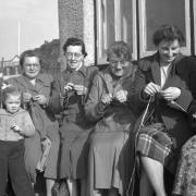 Herring Fishing in Great Yarmouth, the fishergirls knitting during a break on the harbour quayside, 1953. Photo: Archant Library