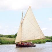 A boat from the hunters fleet sailing on the River Bure near St Benets Abbey on the Norfolk Broads