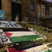 Palestinian flags draped across the steps of City Hall by protestors