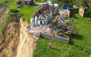 An 18th century farmhouse has been demolished after hanging perilously over a cliff at Trimingham on the north Norfolk coast
